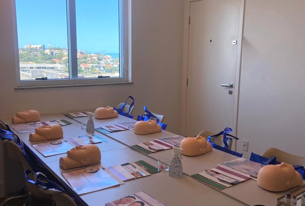 Sala do curso preparada com manequins e apostilas, com vista para o mar